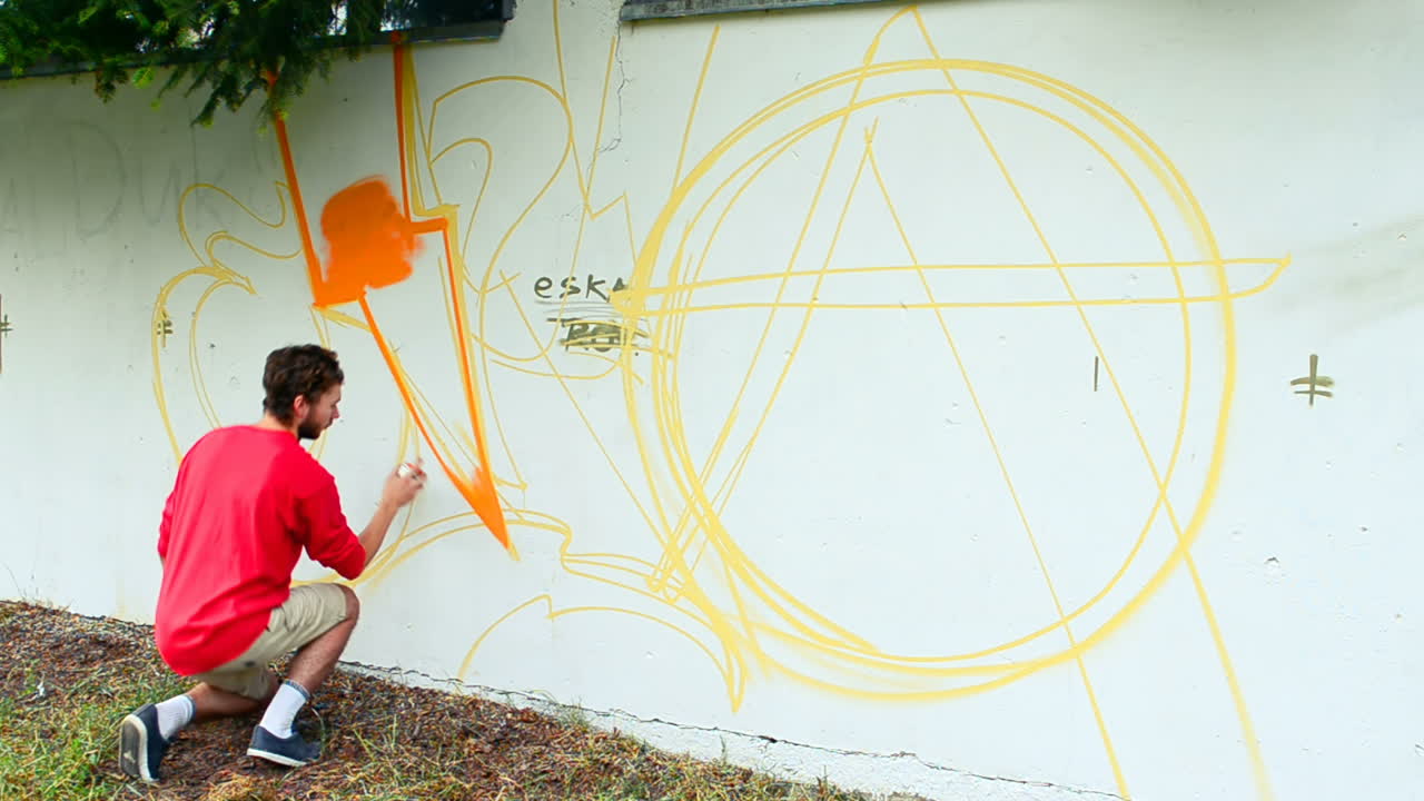 The artist draws graffiti on a fence. Abstract drawing