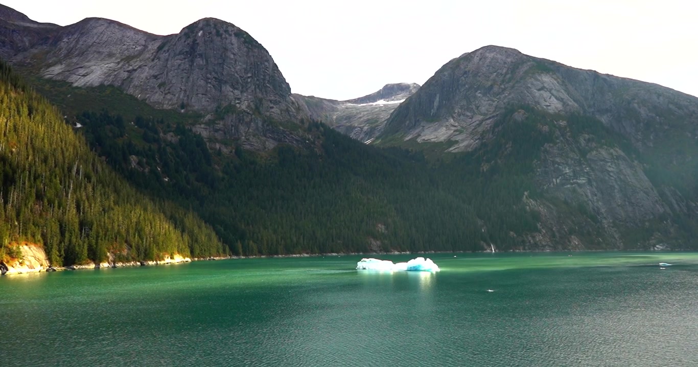 Luce solare che illumina iceberg e parete rocciosa nel fiordo di Tracy Arm, Alaska.