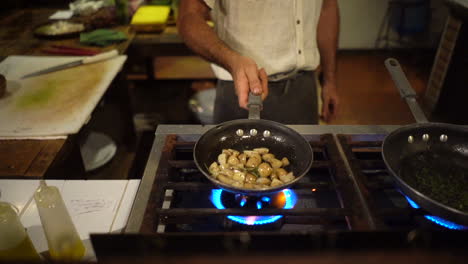 chef hand sautéing potatoes with a frying pan on the stove