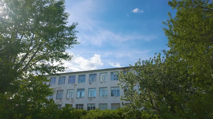 Un edificio circondato da alberi con uno sfondo di cielo blu in Kazakistan, Asia Centrale - Ripresa dal basso.
