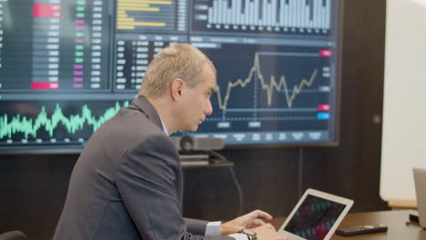 data engineer typing on laptop in meeting room and talking to his colleagues