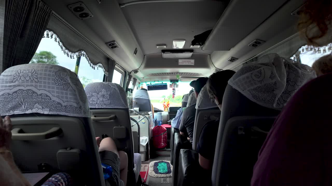 Tourists riding a tour bus through the countryside of a southeast asian country, experiencing local transportation