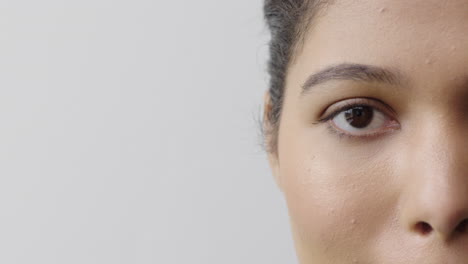 cerca de la mujer hispana ojo mirando a la cámara parpadeando mitad de la cara aislada en fondo blanco copia espacio concepto de cuidado de la piel