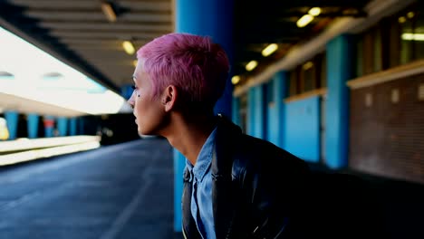 pink hair woman waiting for train in railway station 4k