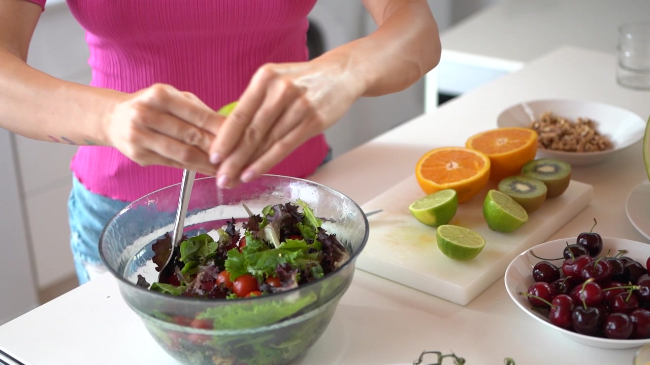 Mulher irreconhecível adicionando suco de limão na salada na cozinha.