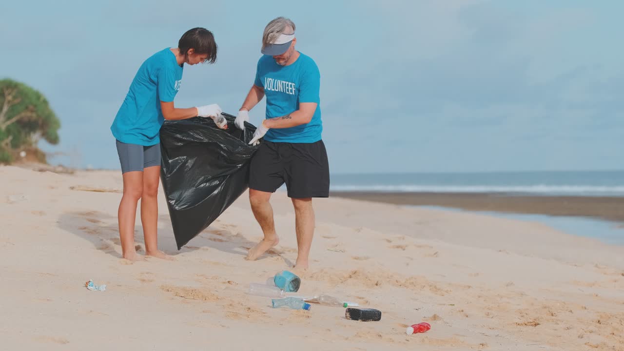 Young caucasian man and woman cleaning up plastic garbage from beach