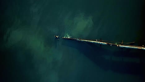 Slow-spinning-aerial-top-down-shot-of-rusty-leaking-pipe-running-into-lake-surrounded-by-mangroves,-dumping-sewage