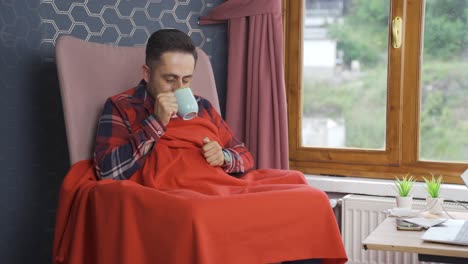 the man who consumes a hot drink in front of the window touches the honeycomb.