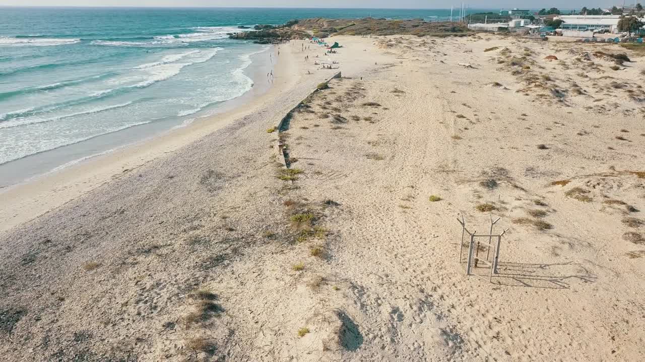 воздушный полет выше, бирюзовый океан, с видом на пляж и отдыхающих на расстоянии. воздушный полёт 4k видео