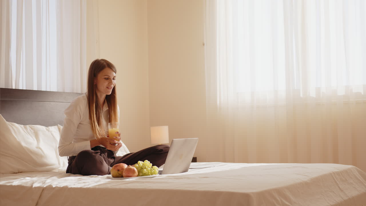 여성이 아침 식사와 함께 침대에서 비디오 통화를 하고 있습니다.
