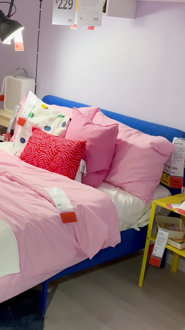 Una vivace configurazione di camera da letto con biancheria da letto rosa, una porta gialla e mobili da studio organizzati.