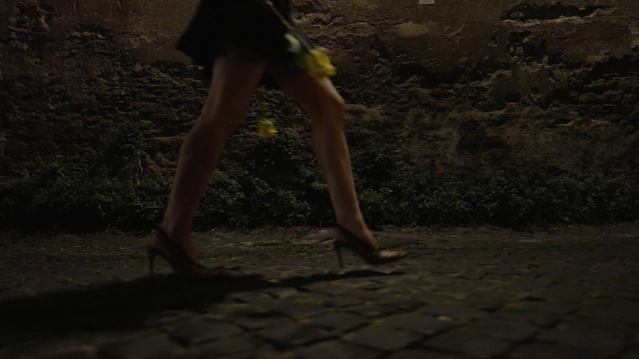 female walking alone home at night, holding a yellow rose and wearing high heel shoes