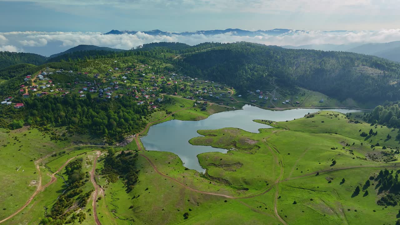 Lush green landscape with serene lake and rolling hills under cloudy sky