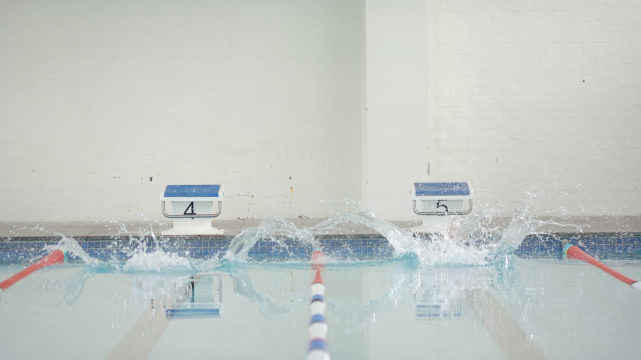Swimming in pool, two swimmers diving into water from starting blocks, copy space