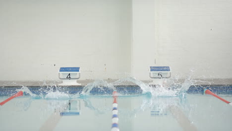 swimming in pool, two swimmers diving into water from starting blocks, copy space
