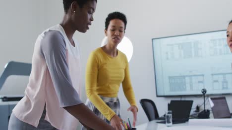 Group-of-diverse-businesswomen-in-discussion-standing-over-desk-in-meeting