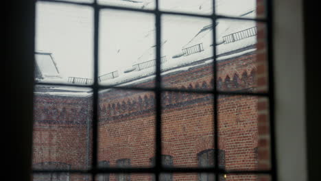 snow gently falls outside a vintage window, serene urban winter scene