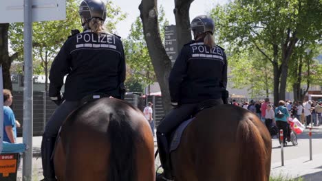 mounted police officers patrol a busy street during a daytime event