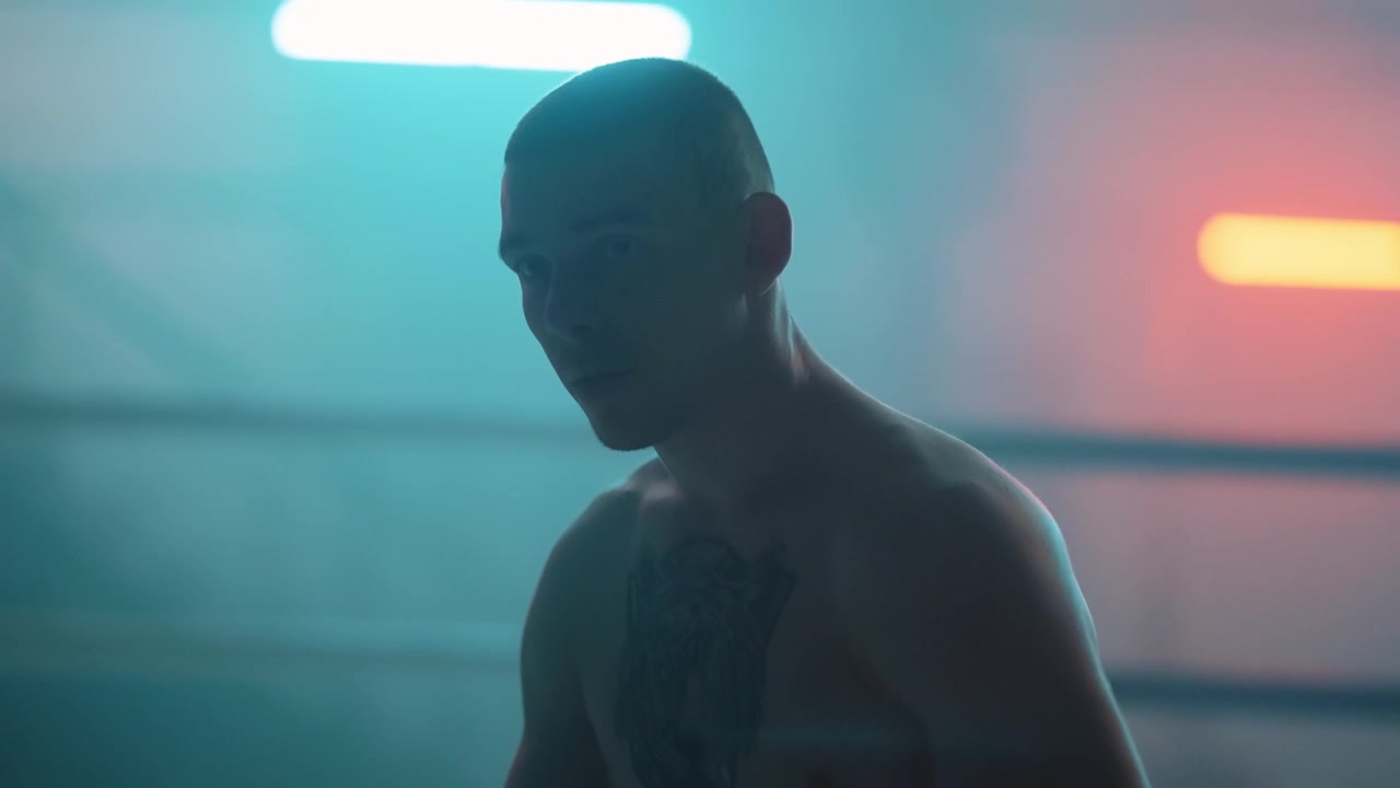 Serious Young Boxer Standing in a Dramatic Neon-Lit Ring