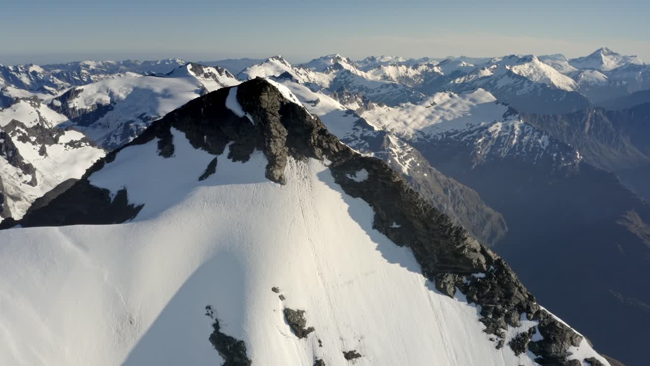 enorme montaña con roca y nieve en la cima entre una espectacular cadena montañosa muy por encima de los valles en nueva zelanda durante el amanecer
