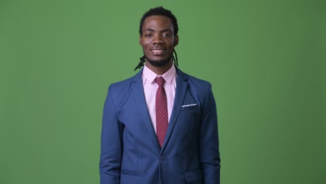 young handsome african businessman with dreadlocks against green background