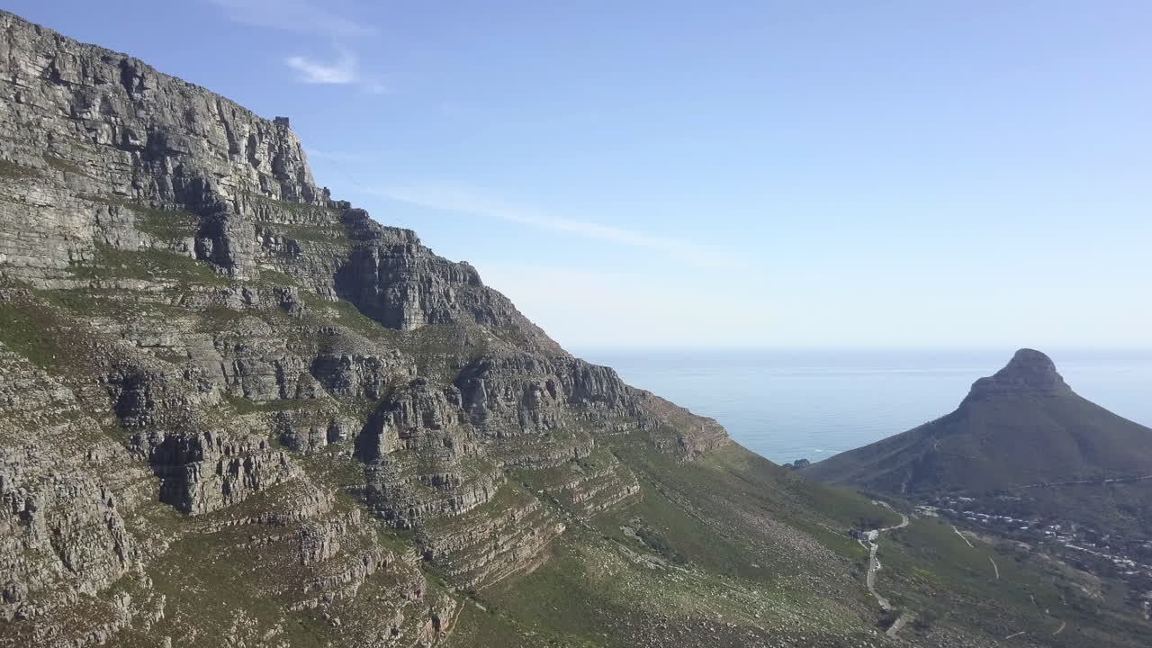 Filmato aereo 4K di alta qualità con cielo blu e soleggiato della spettacolare e panoramica montagna Lion's Head, colline rocciose con sentieri escursionistici, panorama costiero dell'Oceano Atlantico nel Capo Occidentale, Città del Capo, Sudafrica