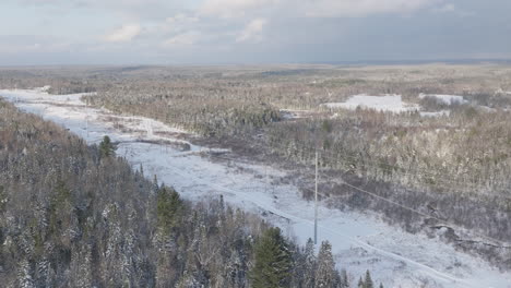 Líneas-De-Transmisión-De-Energía-En-Un-Paisaje-Forestal-Nevado-De-Invierno,-Aéreo