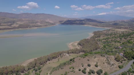 Toma-Aérea-De-Establecimiento-Del-Lago-Seco-De-Pozzillo-Cerca-De-Regalbuto-En-Las-Montañas-Erei-Con-El-Volcán-Etna---Problema-De-Sequía-En-Italia