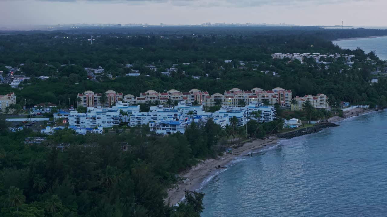 Aerial: Loiza cityscape with sand beach, Atlantic Ocean at sunset in Puerto Rico, USA, establishing drone shot