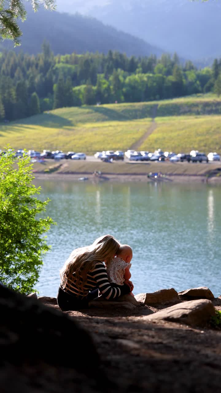 Mother holds her baby on a lakeside rock, a peaceful safe haven