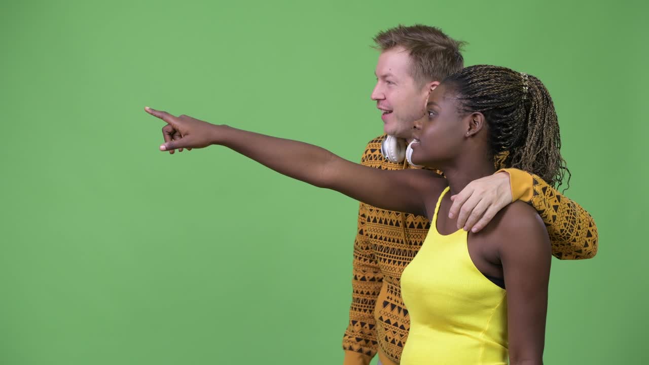Jovem casal multiétnico apontando o dedo juntos