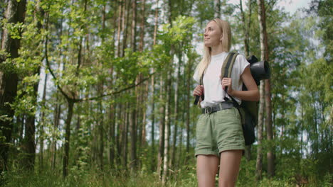 retrato: viajando feliz mujer rubia caucásica con mochila caminando por el camino del bosque tropical