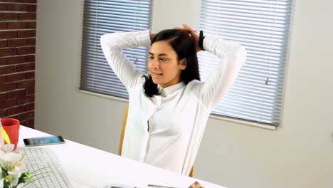 tired businesswoman relaxing at her desk while working on computer