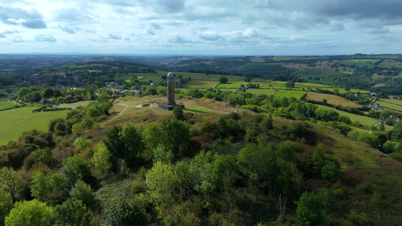 Drone overflight of Crick War Memorial on hilltop overlooking valleys, green meadows, and farmland in Derbyshire, England