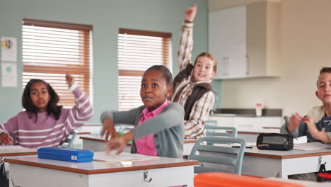 students raising hands in classroom