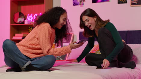 two young women using smartphones in a bedroom