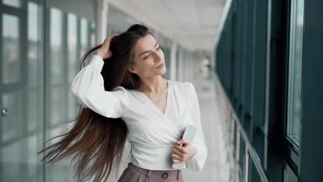 mujer joven con estilo con una tableta posando en un pasillo de cristal