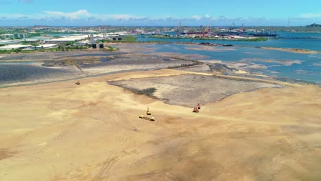 el dolly aéreo de drones se inclina hacia abajo a la excavadora y el cargador en el pozo de limpieza del lago de asfalto arenoso en curacao