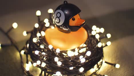 fotografía en primer plano de un pato de goma con un casco de motocicleta hecho a mano sobre el fondo de una guirnalda de navidad