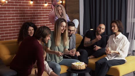 positive womenand men sitting on the sofa gonna eat cake together