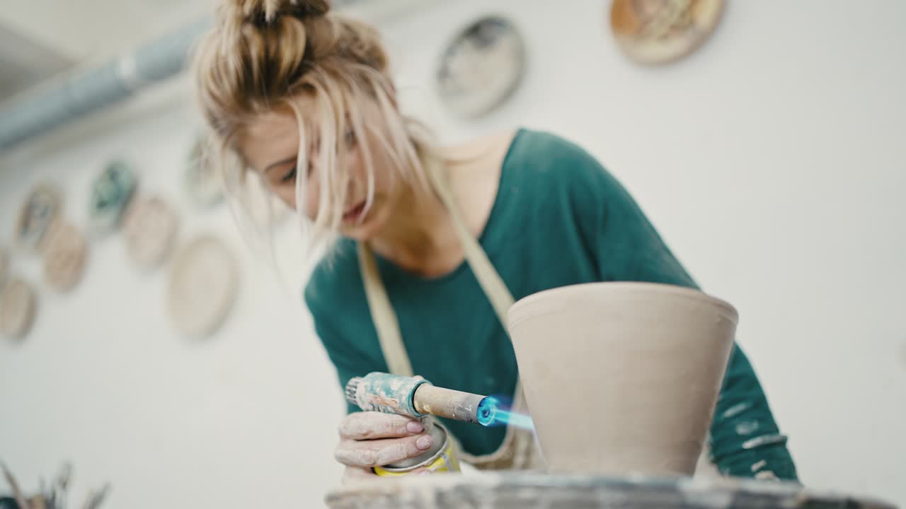 스튜디오에서 세라 물건을 만드는 여성, 도자기 바에 비를 태우는, 아래의 시각, 느린 동작