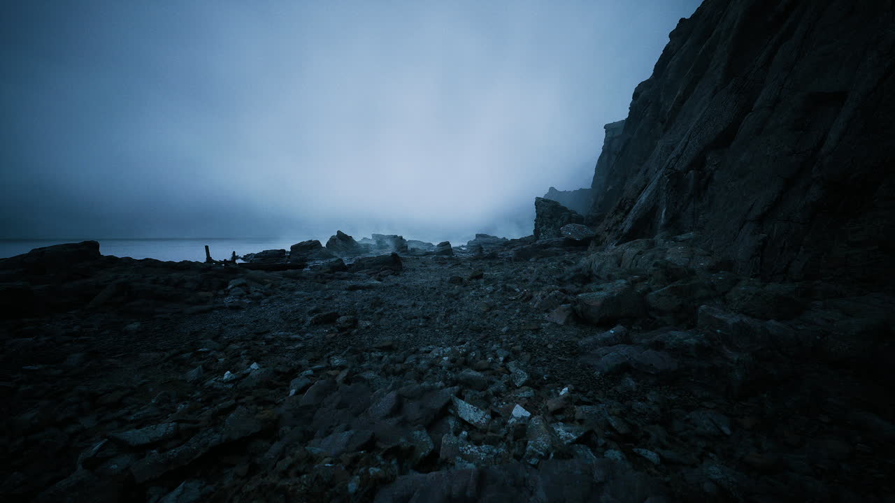Desolate rocky shoreline under cloudy sky with tranquil waters