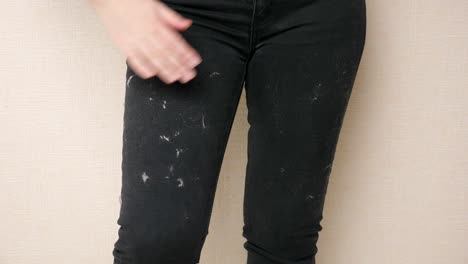 woman tries to clean black pants covered with animal hair