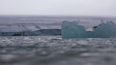 iceberg in cold glacial water under glacier, cinematic slow motion