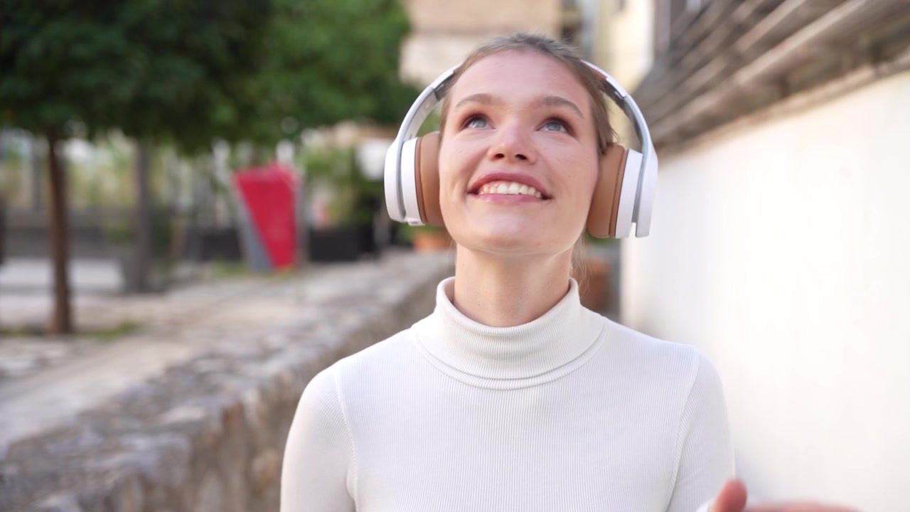 Una giovane donna felice si gode la musica con cuffie alla moda all'aperto.