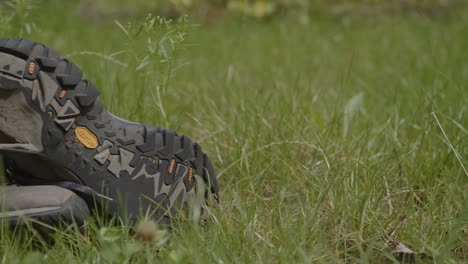 Close-dolly-of-worn-hiking-shoes-lying-discarded-in-a-field
