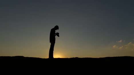 Fotógrafo-De-Silueta-Puesta-De-Sol-Cielo-Despejado,-Fotografiar-Y-Luego-Mirar-A-La-Cámara