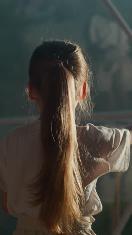 child plays with reflection in window at glamping. little girl does elegant dancing gestures under glass dome in hotel. active kid in luxury hotel