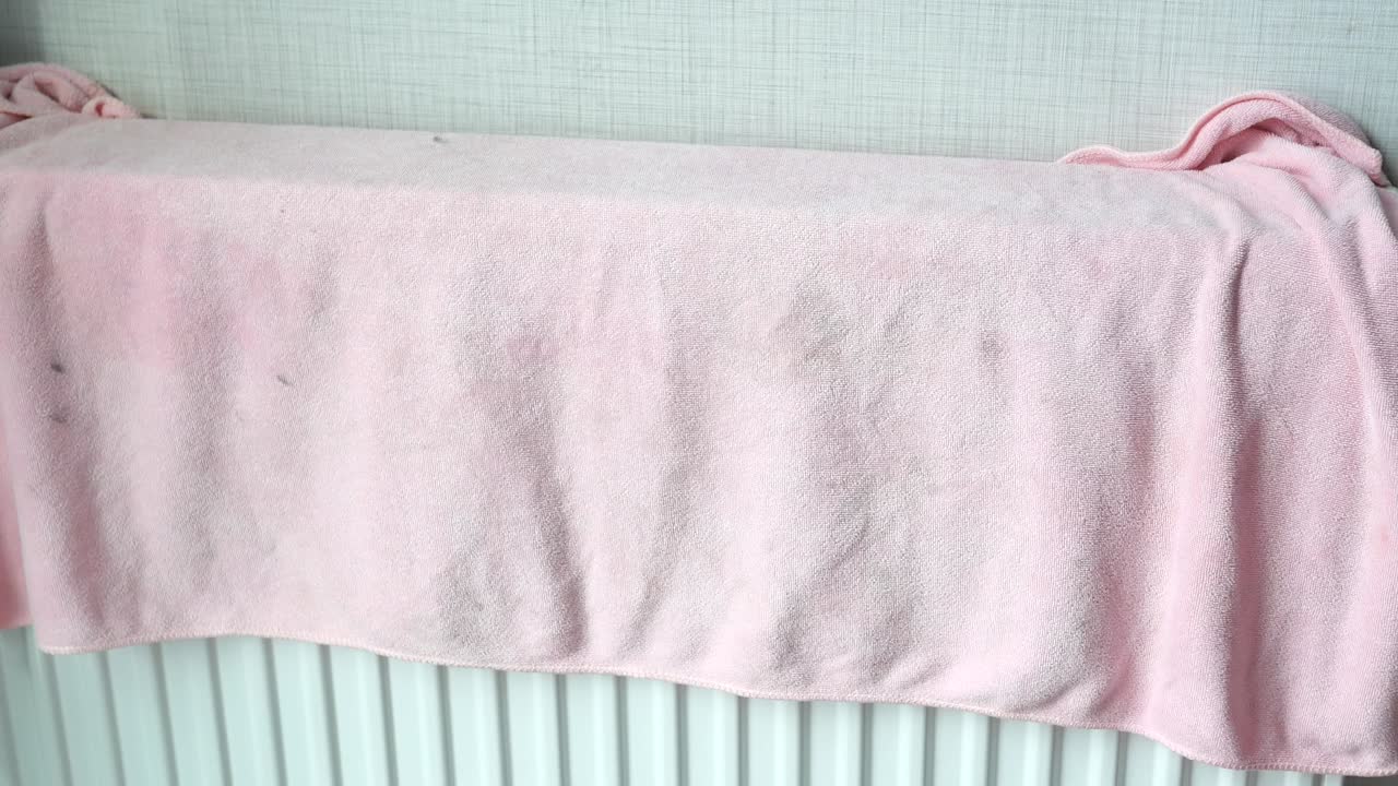 розовое полотенце, покрывающее радиатор