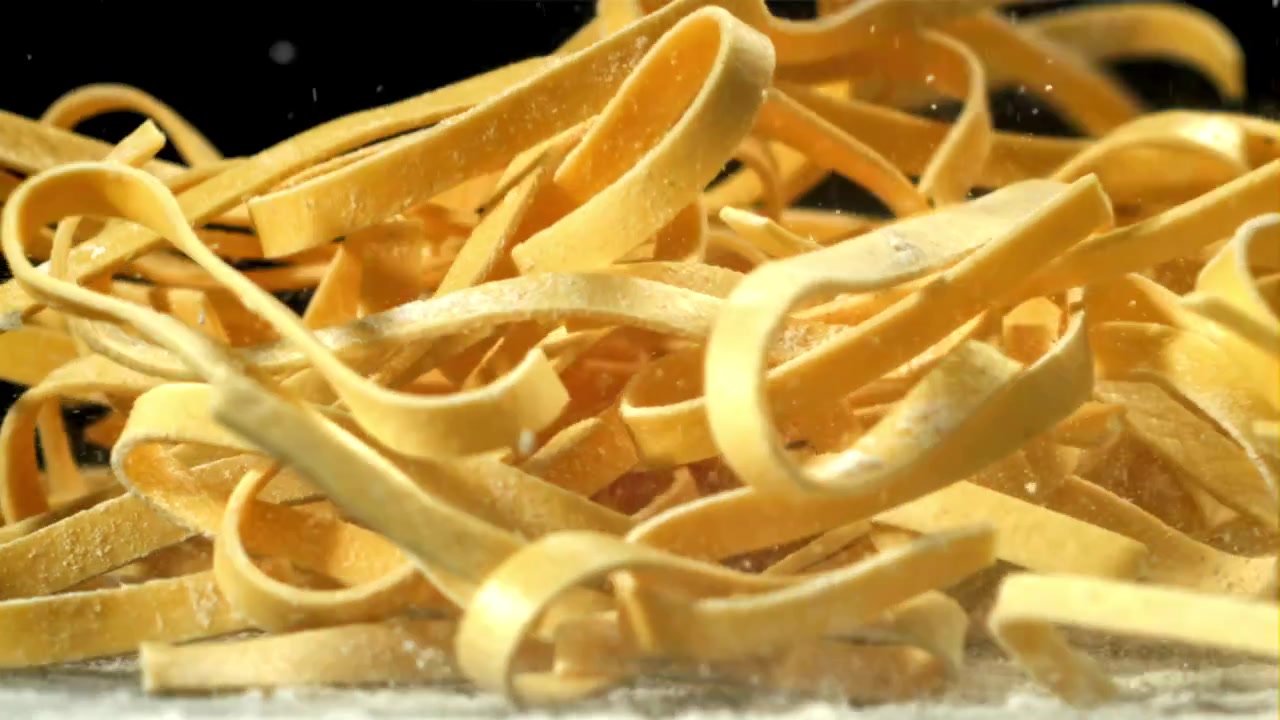 Tagliatelle fresche che cadono sulla farina al rallentatore